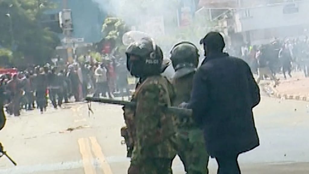 John Kaboi, the plain-clothes police officer heard urging his colleagues to "kill" outside parliamentThis is the police officer - looking towards the camera with his visor lifted - identified by the BBC as the man who killed David Chege and Ericsson Mutisya