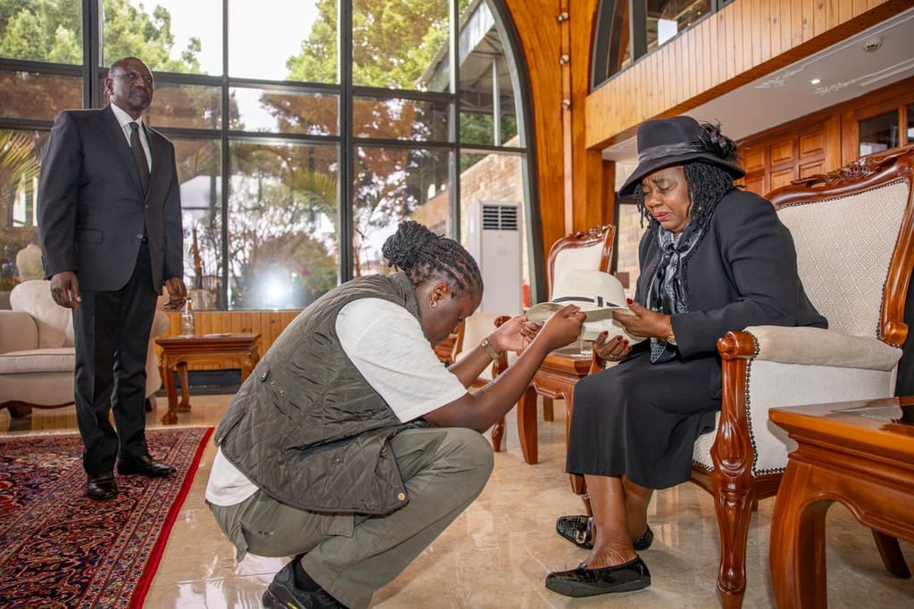 Youngest daughter to the late former Prime Minister Raila Odinga, Winnie Odinga, hands her father's white fedora hat to her mother, Mama Ida Odinga, inside the VVIP offices at the Jomo Kenyatta International Airport.